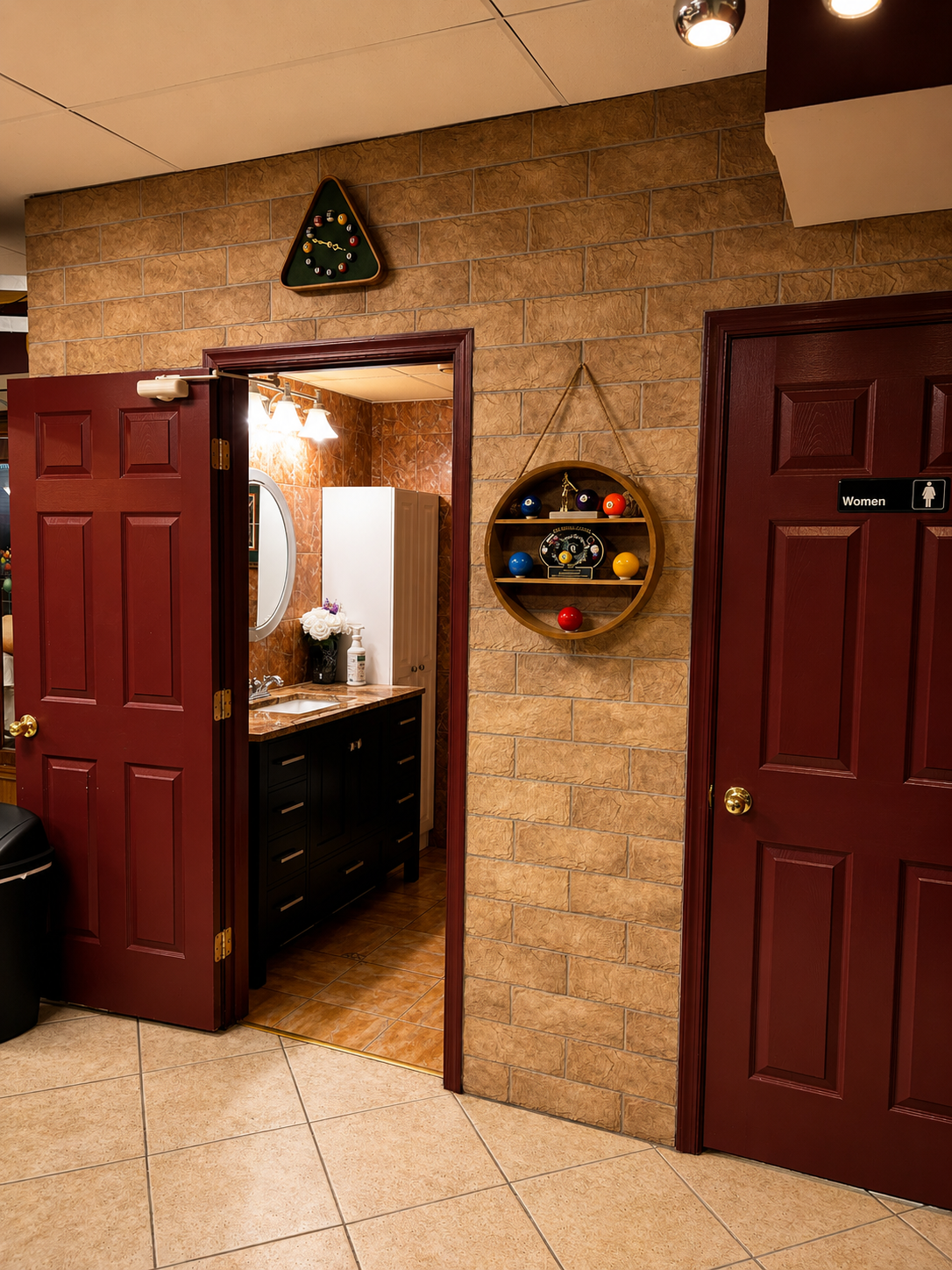 Entrance to the women's restroom with a billiards-rack clock and polished vanity at Gentlemen's Cue Club