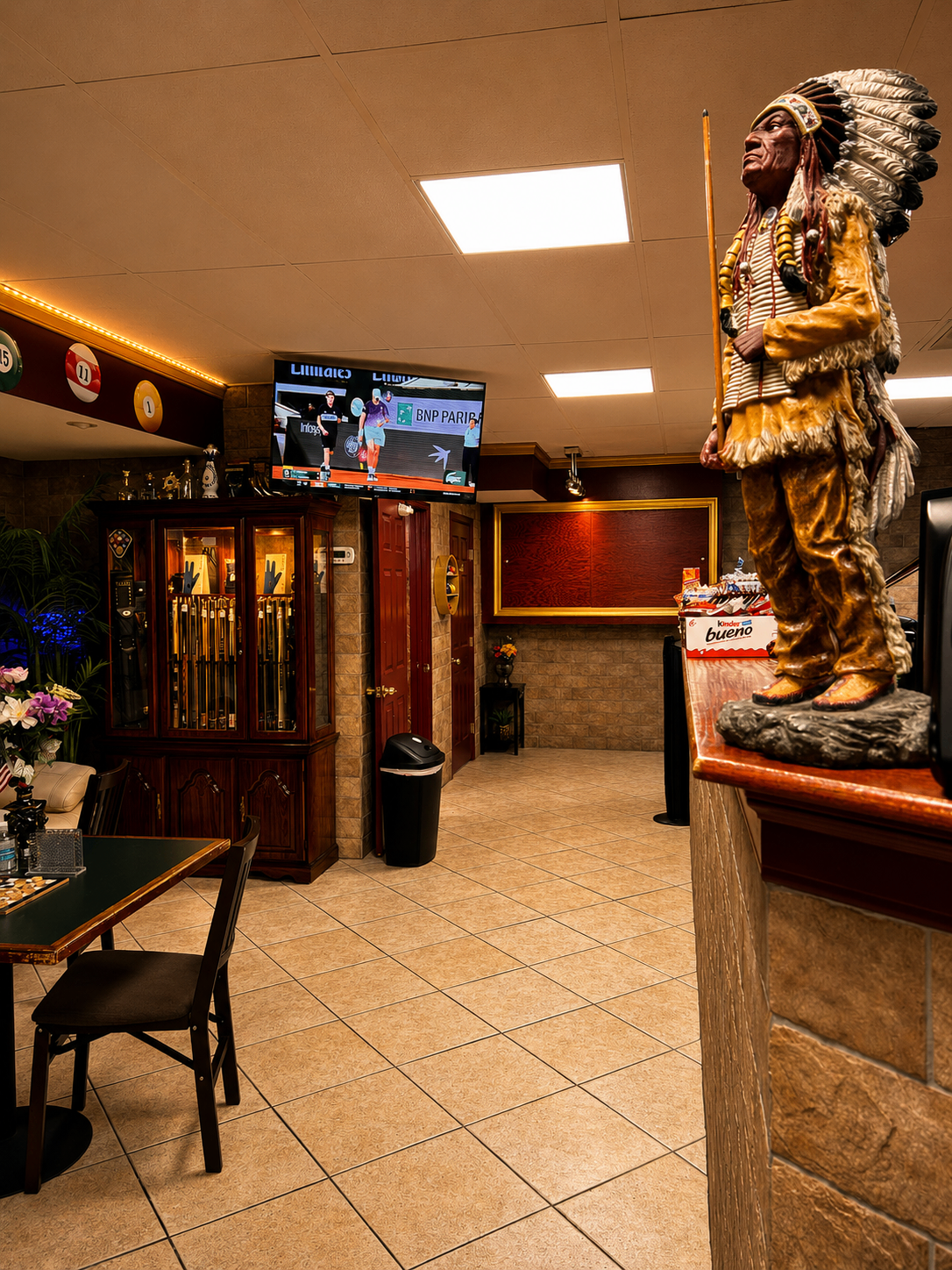 Cue-stick cabinet, trophy display, and hand-carved chief sculpture watching over the lounge