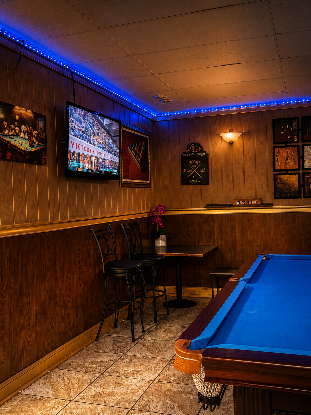 Blue-felt billiards table with wood-paneled walls and accent lighting